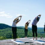 femmes qui font du yoga au sommet d'une montagne