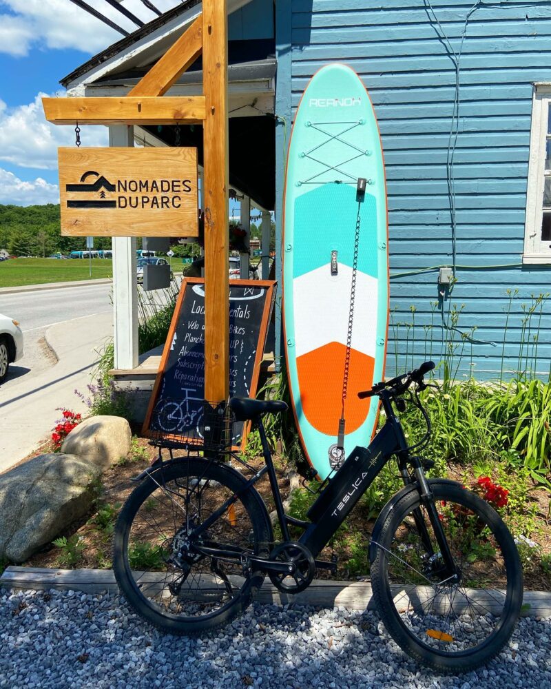 Planche à pagaie et vélo de montagne devant la boutique Nomades du parc