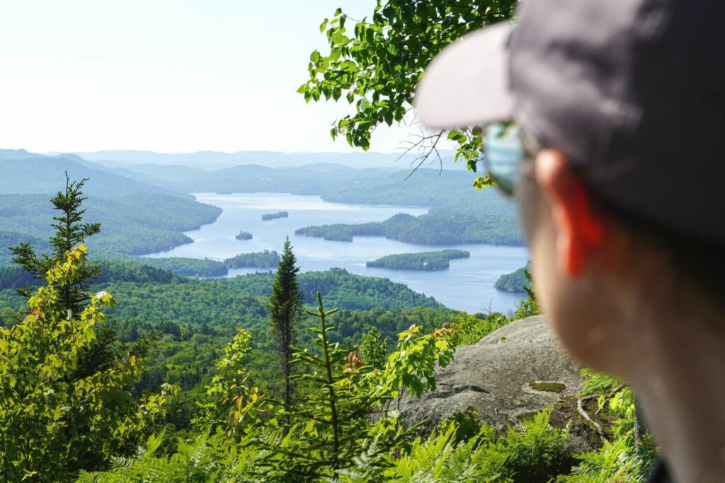 Une personne de dos devant un beau paysage en nature avec un lac en arrière plan