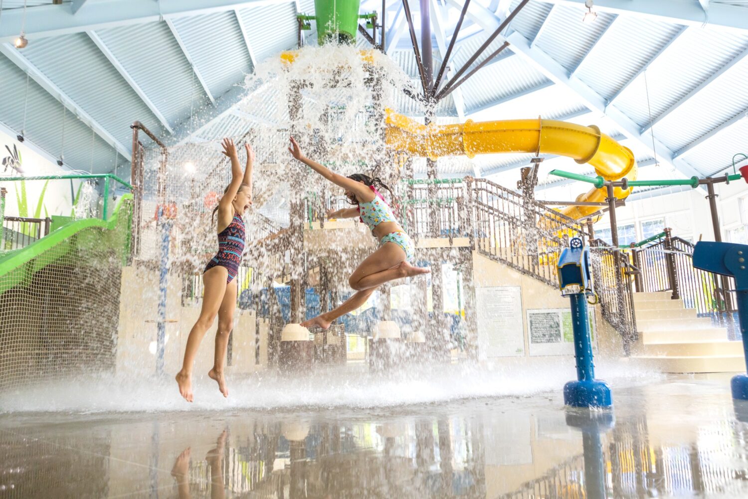 deux enfants qui jouent dans des jeux d'eau devant une immense structure de jeux d'eau avec des glissades
