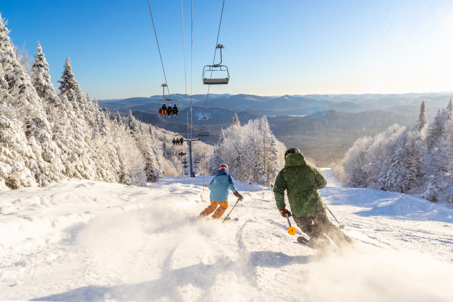 2 personnes descendant le Mont-tremblant en ski et au-dessus d'eux on y voit les télésièges.