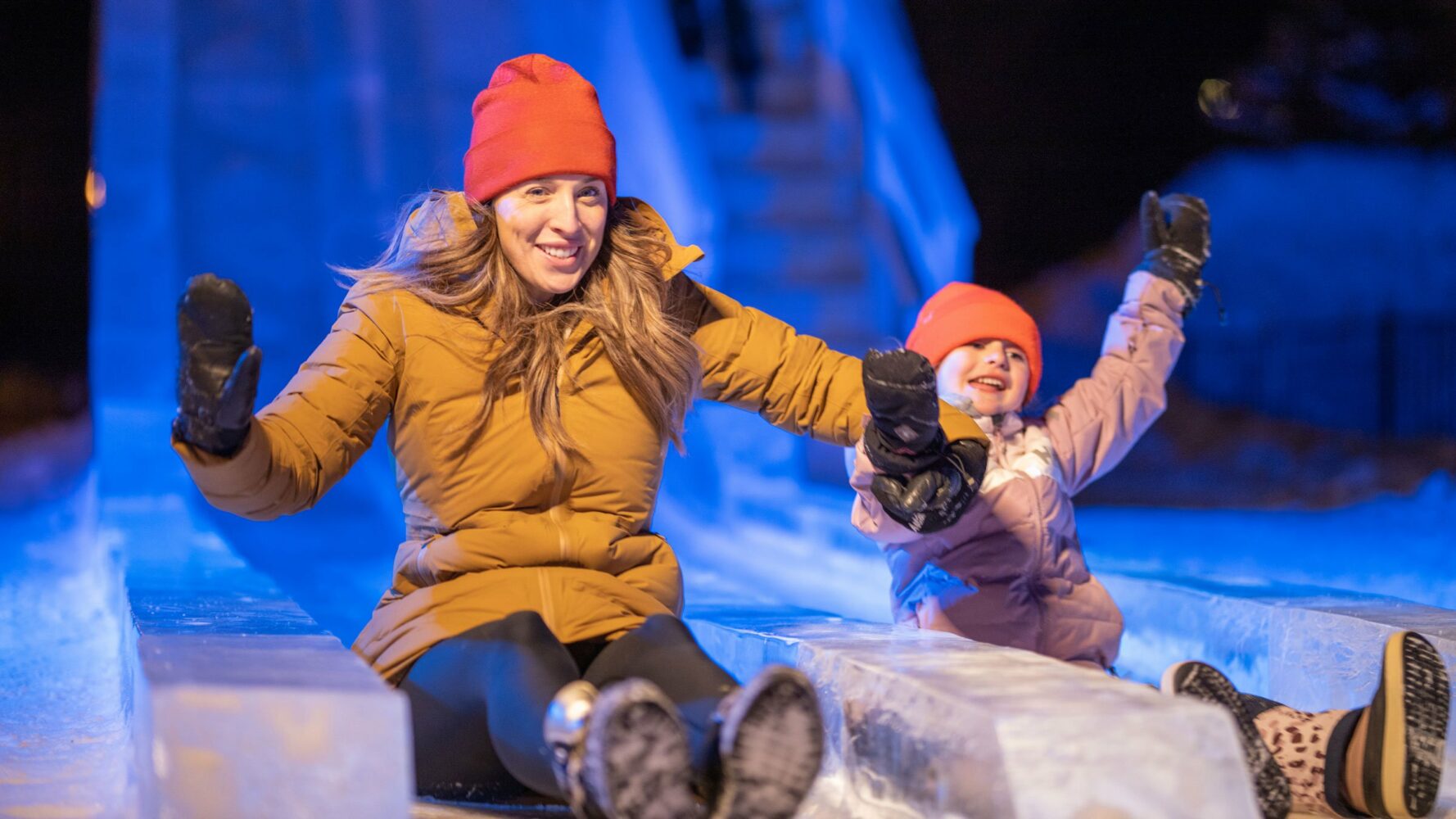Une femme et une enfant qui glisse dans une énorme glissade de glace.