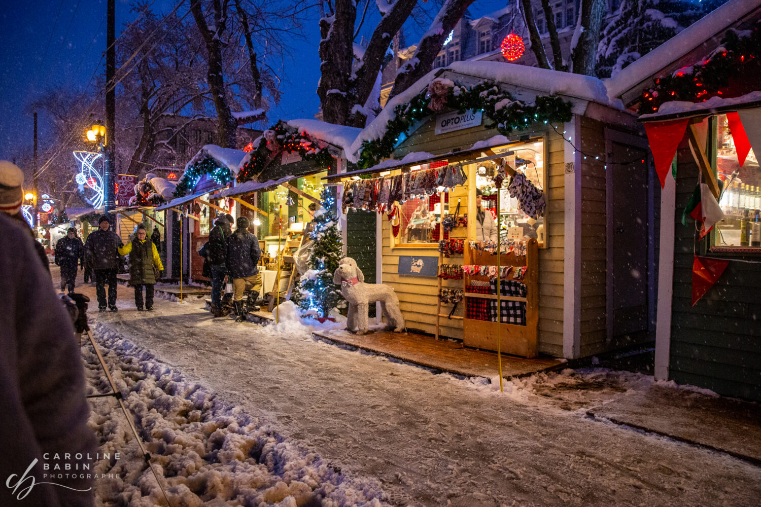 Marché de Noel extérieur, ont peu y voit des gens qui visite le marché, des décorations de Noel et de la neige