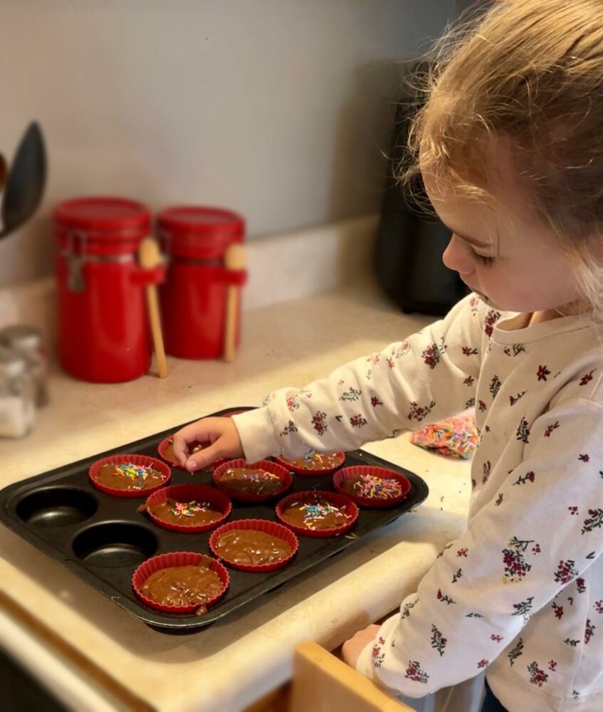 jeune fille qui met des bonbons sur des muffins avant la cuisson