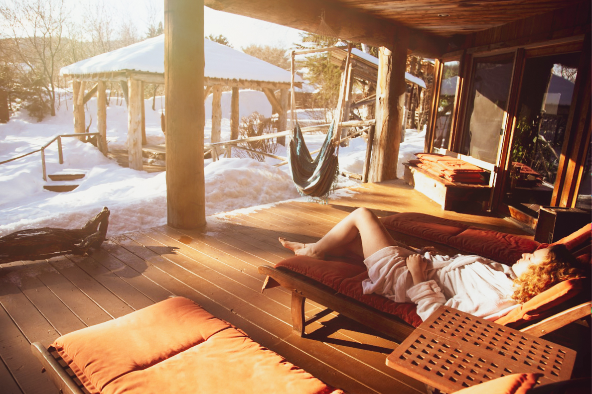 Une femme est étendue dans une chaise longue au soleil, dans un paysage hivernale.