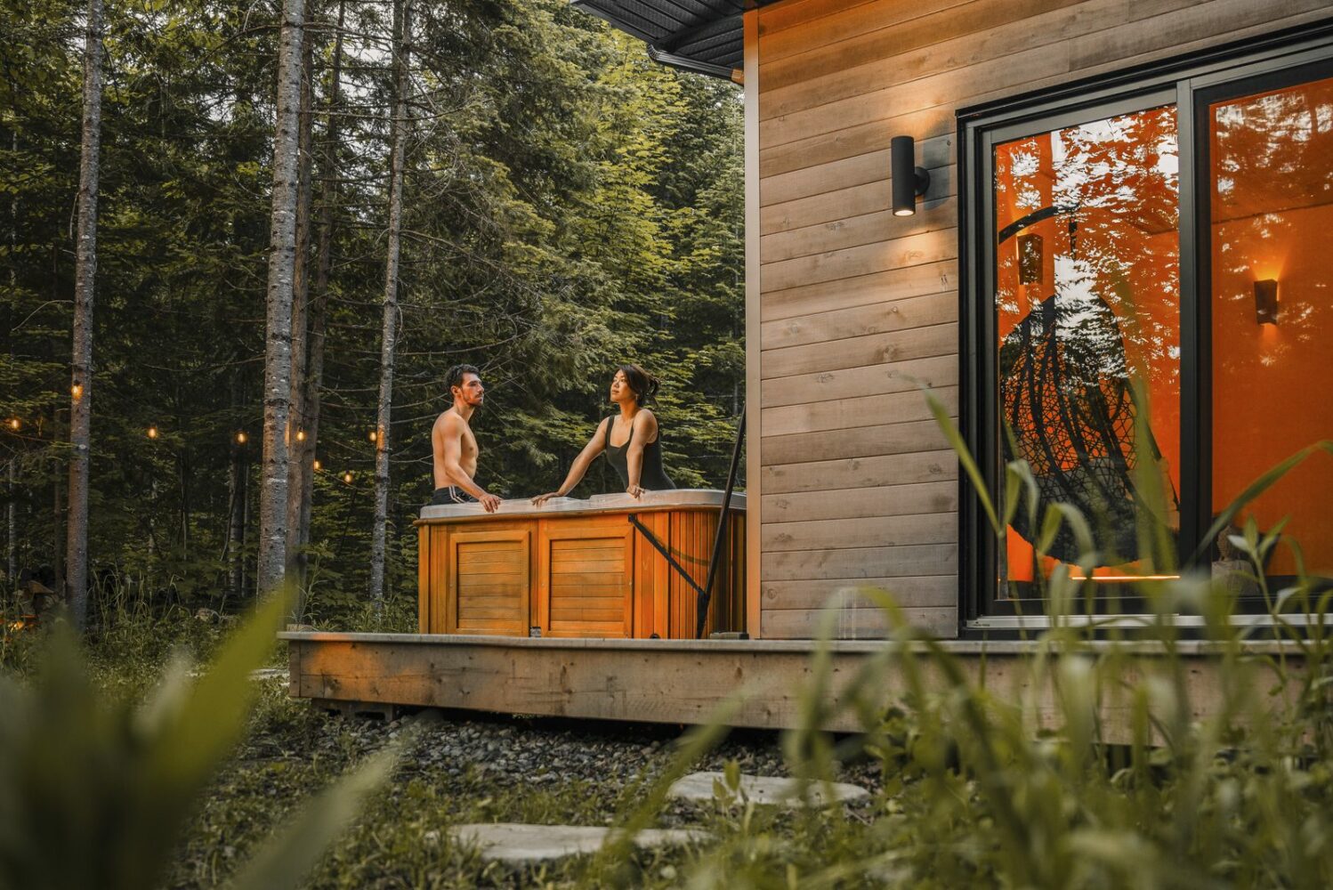 Des gens sont dans le spa d'un chalet et profitent de la nature environnante.