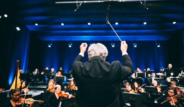 Un chef d'orchestre qui indique à ses musiciens quel temp suivre sur une grande scène