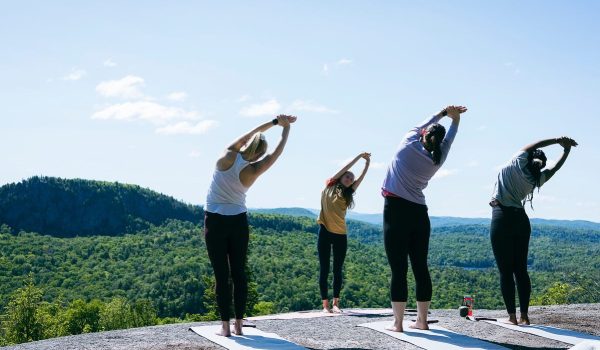 femmes qui font du yoga au sommet d'une montagne