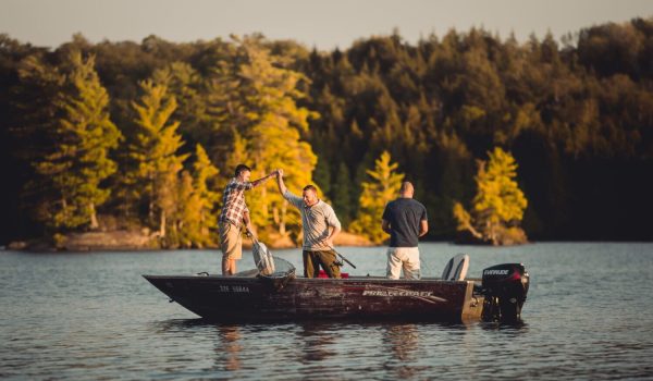 des hommes dans une chaloupe sur un lac sont heureux de leur pêche