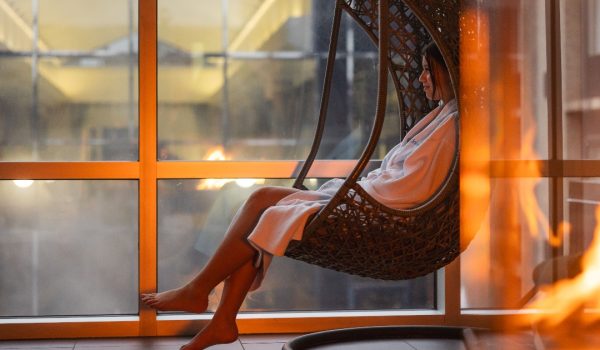 Une femme en peignoir dans une chaise suspendue, relaxant dans les installations intérieures d'Universpa Nordik.